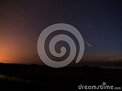 Meteor night sky stars Orion and Taurus constellation Venus over sea Stock Photo