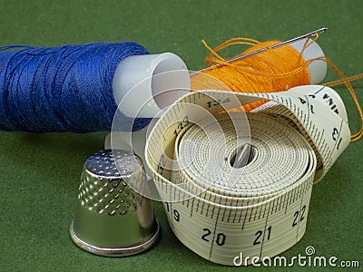 Meter for tailors and multi-colored threads lie on a green background. Stock Photo