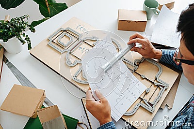 Meticulous box designer working on a blueprint, taking measures with a ruler Stock Photo