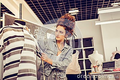 Fashion designer carefuly measuring her new creation. Stock Photo