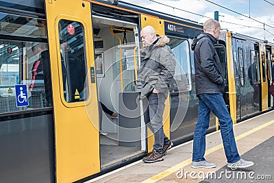 Metro light rail train on a platform in station with people boarding and exiting open doors Editorial Stock Photo