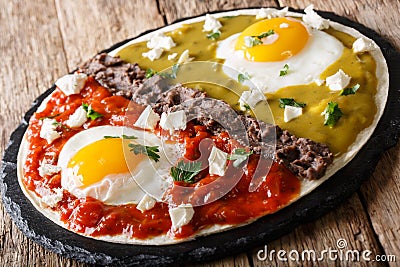 Mexican breakfast huevos divorciados of eggs with Frijoles refritos, sauces roja and verde and cheese Queso Fresco on a corn tort Stock Photo