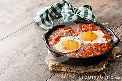 Mexican breakfast: Huevos rancheros in iron frying pan on wood Stock Photo