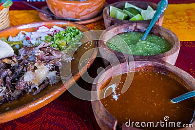 Mexican chopped lamb meat, hot sauces, and lime slices on colorful tablecloth Stock Photo
