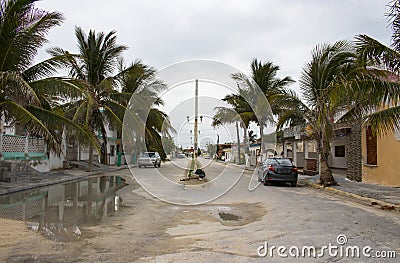 Mexican fishing village street during the rainy season with cars parked along the sides and bag of garbage in the middle of the st Stock Photo