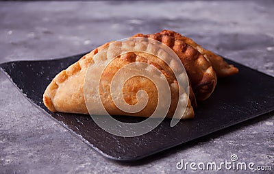 Mexican fried meat pies empanadas cheburek on the black plate on the concrete background Stock Photo