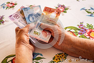Mexican money, a pensioner holds several pesos banknotes in her hand, Financial problems of seniors, low pensions in Mexico Stock Photo
