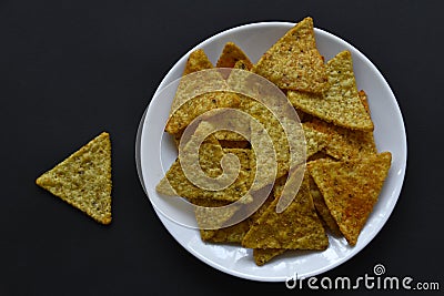 Mexican nachos corn chips with pepper on a white plate on a black background. Delicious breakfast of peppered nachos Stock Photo