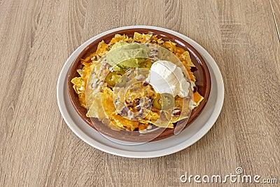 Mexican nachos with guacamole, cream cheese, beans and cheese gratin ready to gobble Stock Photo