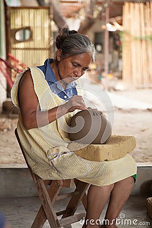 Mexican senior woman cutting designs into barro negro pottery, O Editorial Stock Photo