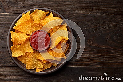 Mexican snack nachos or tortilla in clay plate with dip sauce on rustic wooden background. Stock Photo