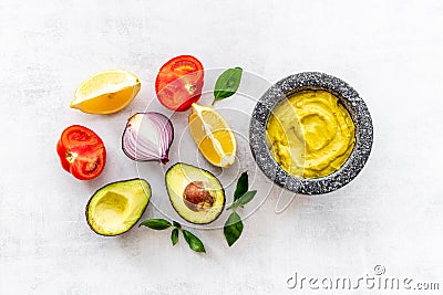 Mexican spicy guacamole avocado dip in mortar with ingredients Stock Photo