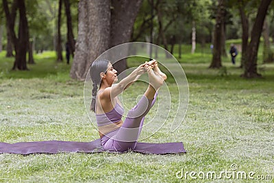 Mexican woman doing yoga exercises in the park on green grass Stock Photo