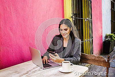 Mexican woman working with her computer on a coffee shop terrace in the streets of a colonial city in Latin America Stock Photo