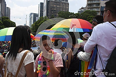People shading themselves from the sun with rainbow coloured umbrellas at the march for LGBTTI pride in Mexico city under natural Editorial Stock Photo