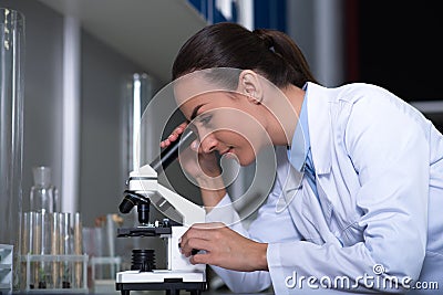 Cute reasonable scientist standing and working with the microscope. Stock Photo