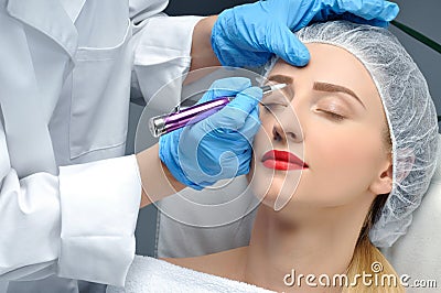 Microblading. Cosmetologist making permanent makeup. Attractive woman getting facial care and tattoo eyebrows Stock Photo