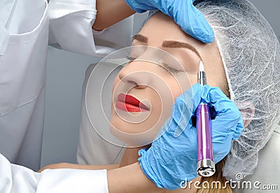 Microblading. Cosmetologist making permanent makeup. Attractive woman getting facial care and tattoo eyebrows Stock Photo