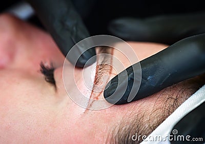 Microblading eyebrows, getting facial care and tattoo at beauty salon Stock Photo