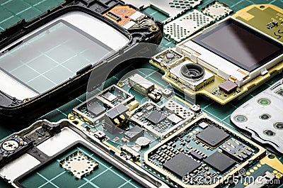 Microchips, semiconductor components and precious metals on the Board of the disassembled old mobile phone close-up on a green bac Stock Photo