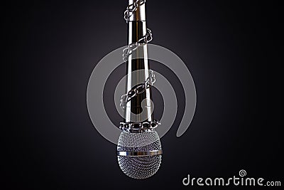 Microphone with a chain, depicting the idea of freedom of the press or freedom of expression on dark background. World press Stock Photo