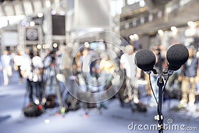Microphone in focus at media event, press or news conference, blurred video camera operators in the background Stock Photo