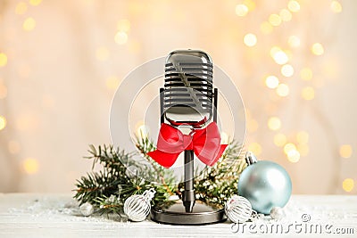 Microphone with red bow and decorations on table against blurred lights. Christmas music Stock Photo