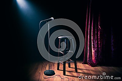 Microphone and wooden stool on a stand up comedy stage with reflectors ray, high contrast image Stock Photo