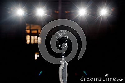 Microphone on the stand with hand nozzle in the center tage with beautiful bokeh spotlights in the background Stock Photo