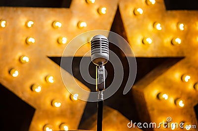 Microphone on theater or karaoke stage, golden luminous star on background Stock Photo