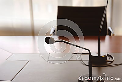 Microphone on a wooden table and an empty chair in a boardroom Stock Photo