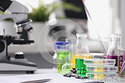 Microscope multicolored liquid in test tubes and papers on table in laboratory Stock Photo