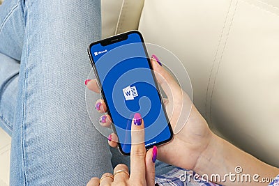 Microsoft Word application icon on Apple iPhone X screen close-up in woman hands. Microsoft office word icon. Microsoft office on Editorial Stock Photo