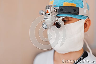 Microsurgeon man in a white mask in special medical clothes and glasses with binocular loupes in the operating room. Stock Photo