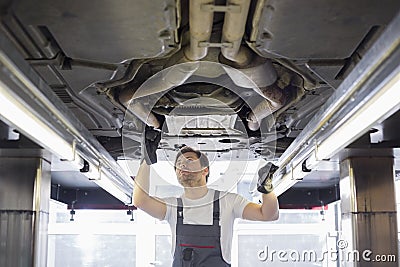 Mid adult male repair worker repairing car in workshop Stock Photo