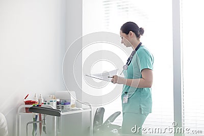 Mid adult nurse checking medical reports on clipboard at hospital Stock Photo