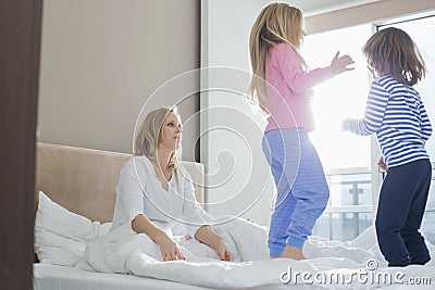 Mid adult parents looking at playful children in bedroom Stock Photo