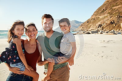 Mid adult white couple standing on a beach each carrying one of their children, front view, close up Stock Photo