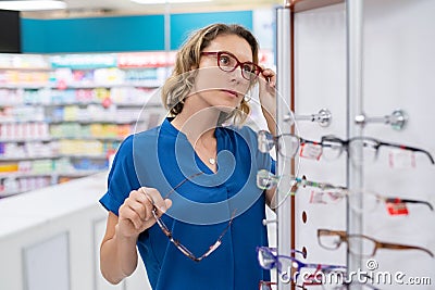 Mid adult woman trying spectacles at optic store Stock Photo