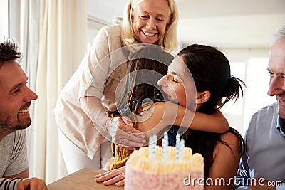 Mid adult woman embracing her daughter after blowing out candles on birthday cake, close up Stock Photo