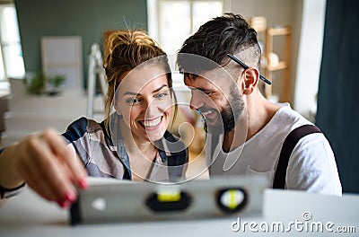 Mid adults couple with leveler indoors at home, relocation and diy concept. Stock Photo