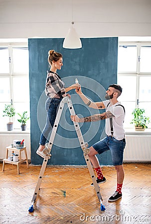 Mid adults couple painting indoors at home, relocation and diy concept. Stock Photo