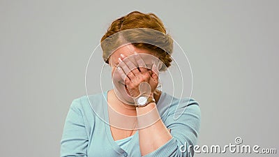 Mid aged actress showing tender emotions, covering her face with palm. Stock Photo