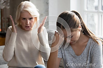 Middle aged mother scolding grown up daughter having difficult relationships Stock Photo