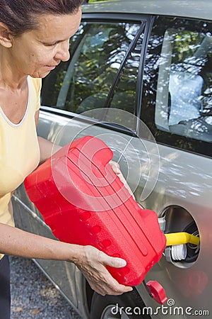 Mid aged woman adding fuel in car Stock Photo