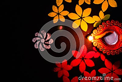 Mid close up of a glowing diya and red white yellow rangoli on black background. festival of light Stock Photo