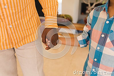 Grandfather and grandson standing hand in hand at home Stock Photo