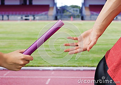 Mid-section of athlete passing the baton to teammate Stock Photo