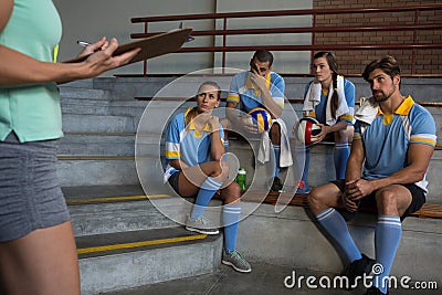 Mid section of coach standing by volleyball players Stock Photo