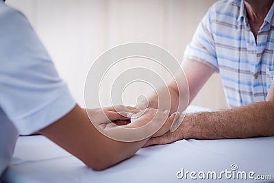 Mid section of female doctor consoling senior man in living room Stock Photo